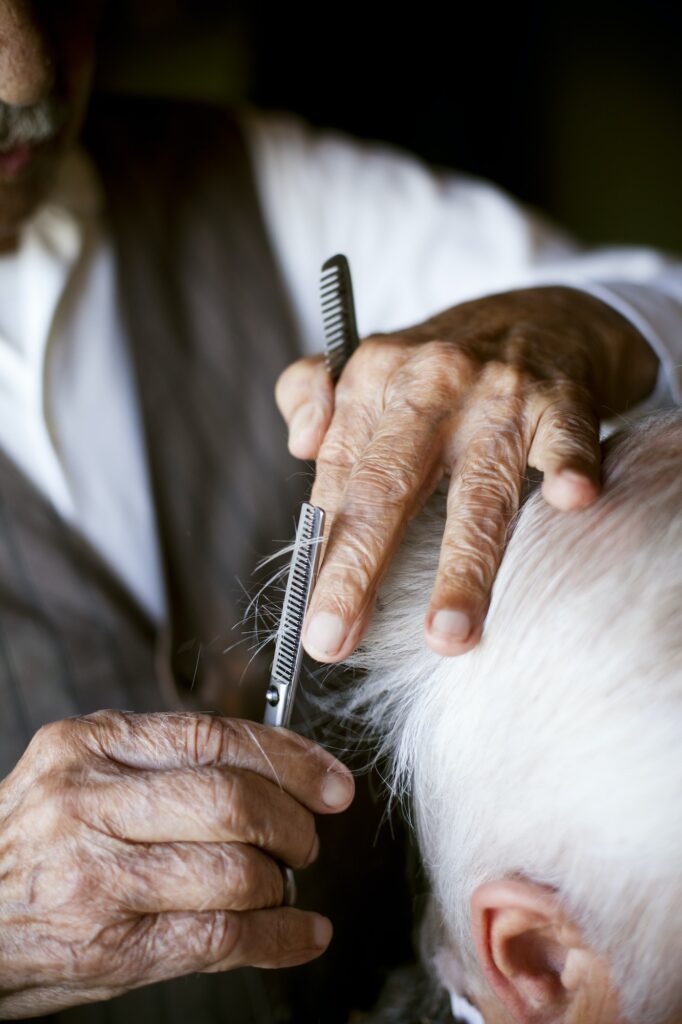 Cropped image of hairdresser giving haircut to senior man